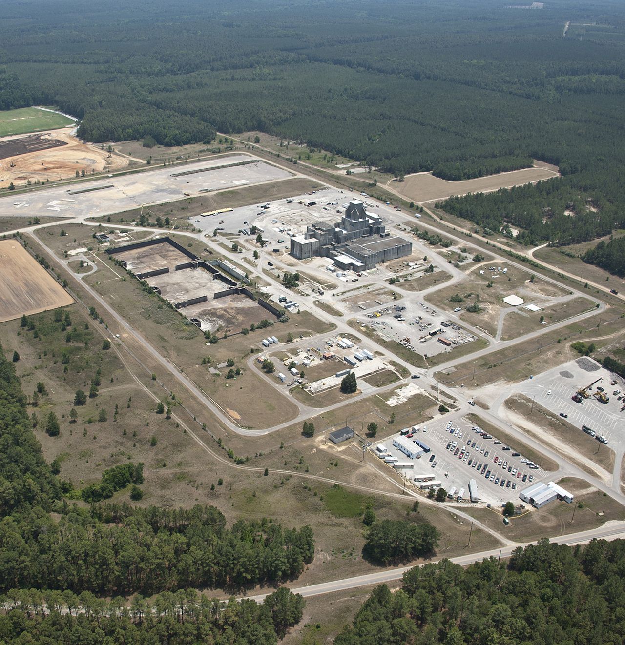 Aerial view of a waste storage and disposal site surrounded by pine forest